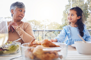 Food, family and grandmother with girl a table for lunch, party or social gathering on a patio. Love, dinner and senior woman looking at grandchild while sharing a meal, happy and smile outdoors