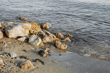 The shore of the reservoir. Sandy beach of a mountain lake with stones.
