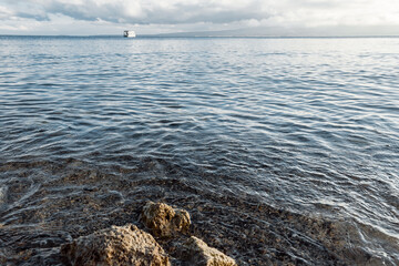 The shore of the reservoir. Sandy beach of a mountain lake with stones.