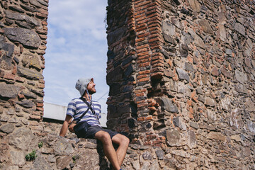 Young latin man smiling and relaxing in the frame of an antique window made of stone. Copy space.