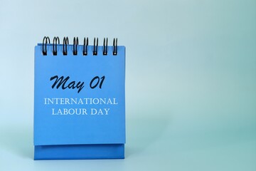 May 1 as International labor Day date reminder on blue desk calendar. Celebration concept.