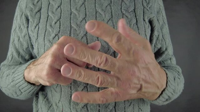 A man rubs his fingers, which hurt and pull. Arthrosis of the joints. Close-Up