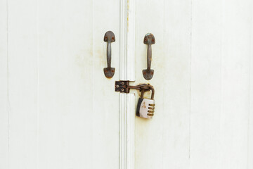 The Closed padlock hangs on the white doors.