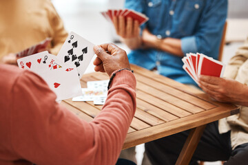 Senior friends, hands or playing card games on wooden table in fun activity, social bonding or gathering. Group of elderly men having fun with cards for poker game enjoying play time together at home