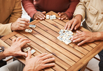 Hands, dominoes and friends in board games on wooden table for fun activity, social bonding or...