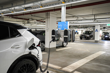 Recharging electric cars at the charging station in the underground parking. The concept of ecological energy systems.