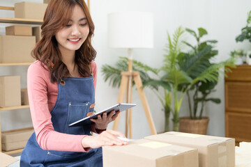 Portrait of Starting small businesses SME owners, Asian woman check online orders Selling products online and working with boxes freelance work at home Asian sme business online medium enterprise.