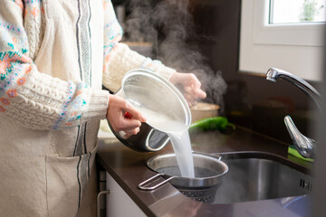 Girl cooking. Girl removing the water from the boiled rice
