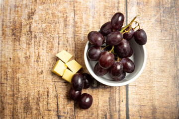 top view of red grapes with cheese on a wooden background