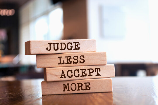 Wooden blocks with words 'JUDGE LESS ACCEPT MORE'.