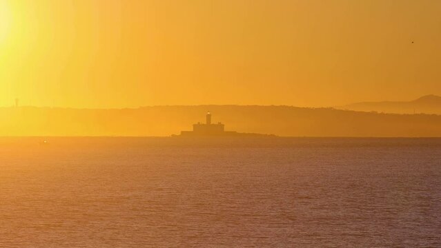 Bugio lighthouse with yellow and reflections sun on top, Carcavelos