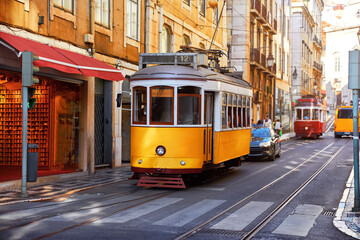 Naklejka na ściany i meble Lisbon, Portugal. Vintage yellow retro tram on narrow bystreet tramline in Alfama district of old town. Popular touristic attraction Lisboa city