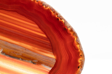 White, dark and light orange, red semi-transparent agate slice crystal, straight bands of silica chalcedony stone isolated on a white background surface with detail. Abstract crystal with copy space