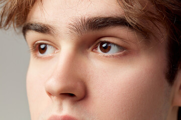 Obraz premium Looking away. Close-up portrait of young man with brown eyes. Eyes, nose. Vision care. Concept of men's health, body and skin care, hygiene and male cosmetology