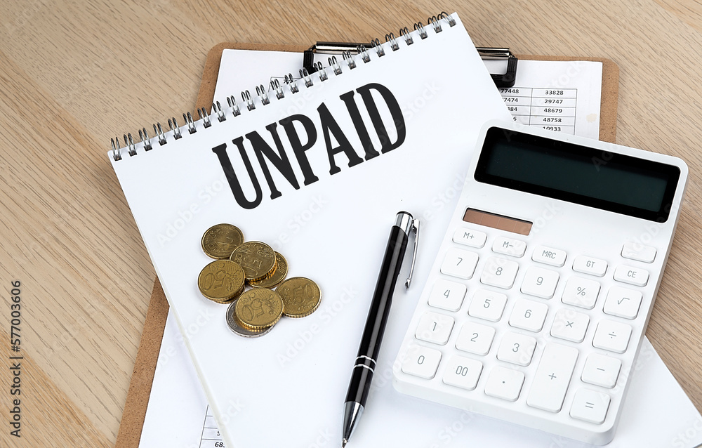 Poster unpaid text on a notebook with chart and calculator and coins, business concept