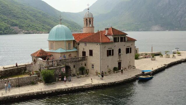 Perast, Montenegro, may 2022: Island with an historic church Our lady of the rock in Kotor bay. Tourists walk on island