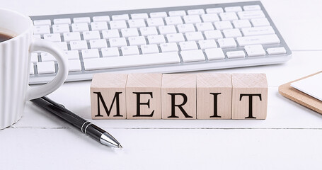 MERIT word on the wooden blocks with keyboard and coffee