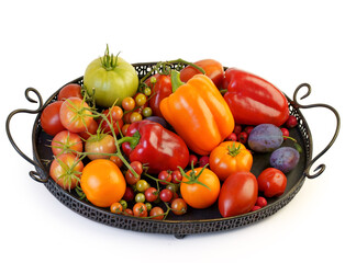 Tomatoes of various varieties and sizes on an iron tray on a wooden table.