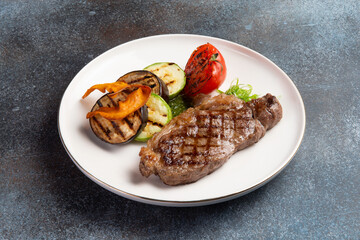 Striploin steak and grilled vegetables in a plate.