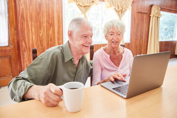 Senior couple in retirement home sitting at laptop computer
