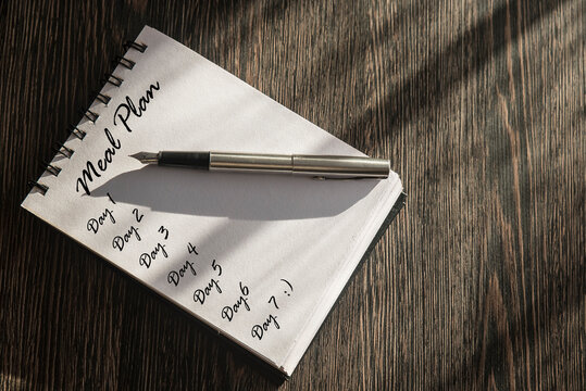 zapisana kartka w notesie ponumerowanymi dniami z napisem Meal Plan. Koncepcja diety, zdrowego żywienia.