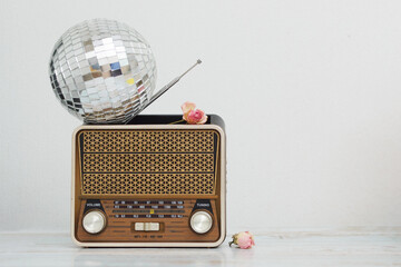 The vintage style of the old retro radio on which the round disco ball lies on the table against...