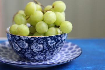 Fruit on a blue decorative crockery. Close up photo of beautifully patterned tableware. Textured backdrop with copy space. 