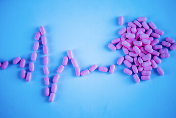 A handful of vitamins and pills in the shape of a heart and a cardiogram line. Medical background. Medical first aid kit and medicine concept.