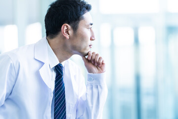 外を見つめる白衣を着た本人男性