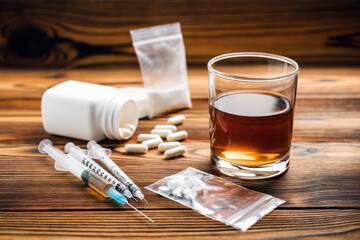 Glass with alcohol drink, whisky or brandy, white pills, syringe with a drugs dose, narcotic in...