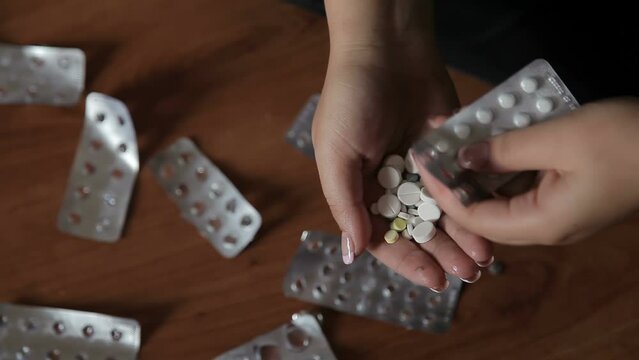 The woman committed suicide by taking an overdose of drugs. Pill poisoning. Poison pills in the hand of a woman who committed suicide due to a drug overdose. Concept of depression or suicide despair