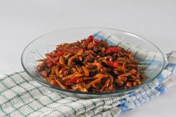 dry cooked anchovies and peanuts, a special Indonesian menu, served in a small plate with a napkin isolated on a white background