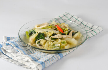 mustard greens and mushrooms are served on a small plate with a napkin isolated on a white background
