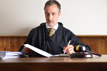 Judge reviewing the summary of a case on wooden table - obrazy, fototapety, plakaty