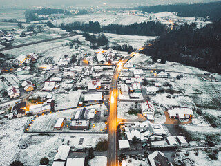 Aerial view of populated rural area on a winter evening, snow covering the grounds, street lights shining in the dark