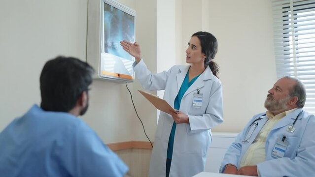 Woman medical assistant talking and explaining the X-ray results of the patient's body and there was an old male doctor sitting there listening at hospital