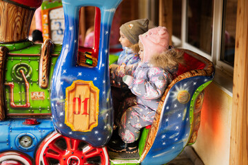 Two sisters in train carousel in amusement park.