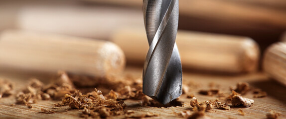 drill bit makes hole in wooden oak board for wooden dowel.