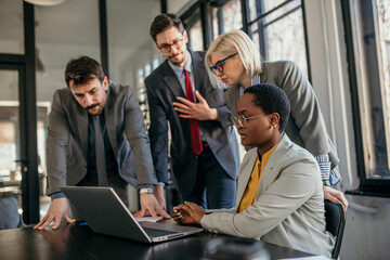 Shot of coworkers discussing in a modern office. Businessman and businesswoman in a discussion using a laptop and debating business strategy.