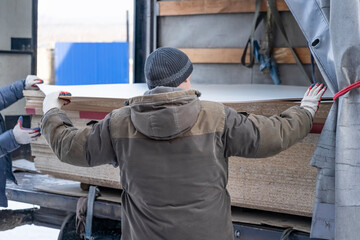 The average adult worker unloads chipboard from a truck.