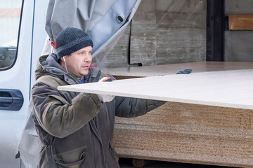 The average adult worker unloads chipboard from a truck.