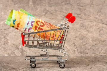 Shopping trolley from a supermarket with roll of euro banknotes