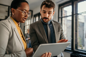 Shot of two dedicated businesspeople discussing something on a digital tablet.