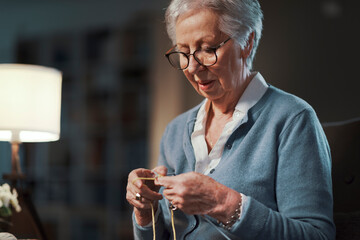 An elderly woman enjoys her leisure time knitting.