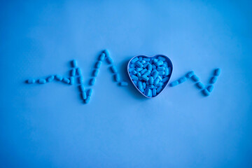 A handful of vitamins and pills in the shape of a heart and a cardiogram line. Medical background. Medical first aid kit and medicine concept.