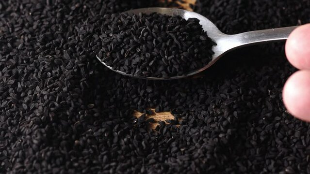 Black cumin seeds with spoon, macro top view