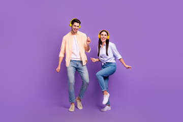 Full size photo of two overjoyed positive people enjoy listen music dancing chilling isolated on violet color background