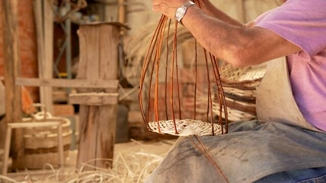 Old man hands weaving willow sticks for making wicker baskets. Close up video. Latin American tradition and culture
