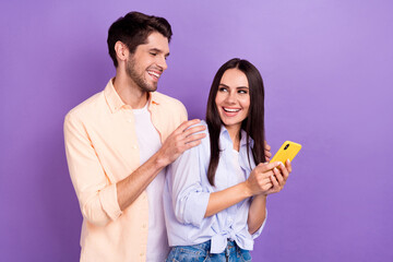 Photo of laughing carefree overjoyed people together friendship hold smartphone enjoy read internet blog isolated on violet color background