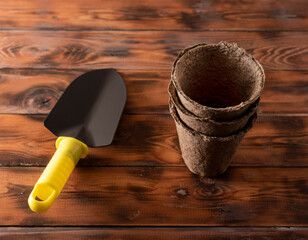 peat cups for planting sprouts and plants with a garden spatula on a wooden background.